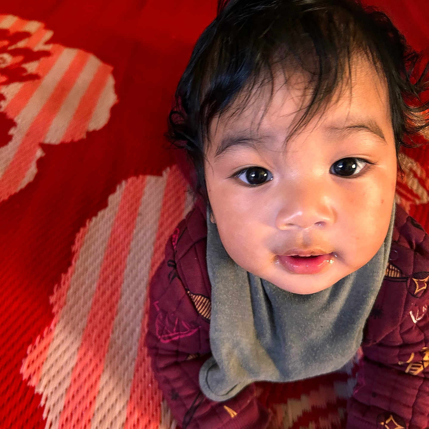 Mohide Ms joined the competition — help win amazing prizes! baby, bib, child, closeup, curious, cute, drool, expression, eyes, face, hair, hands, indoor, infant, jacket, pattern, portrait, red_mat, skin, toddler