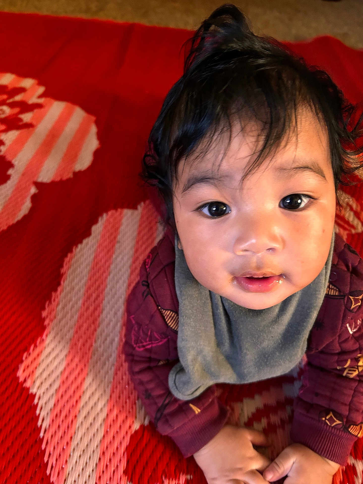 Mohide Ms joined the competition — help win amazing prizes! baby, bib, child, closeup, curious, cute, drool, expression, eyes, face, hair, hands, indoor, infant, jacket, pattern, portrait, red_mat, skin, toddler