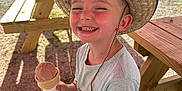Zayden joined the competition — help win amazing prizes! child, boy, smiling, hat, straw_hat, ice_cream, cone, picnic_bench, outdoor, sunlight, summer, happy, casual_clothing, shorts, tshirt, grass, trees, park, daytime, recreation