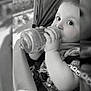 Tiziano participe au concours pour gagner de l'argent avec cette photo : baby, baby_accessory, black_and_white, bottle, child, closeup, clothing, cute, expression, face, feeding, hand, infant, outdoor, person, portrait, seatbelt, sitting, stroller, young_child