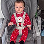 baby, child, high_chair, chicco, red_clothing, polka_dot, santa, onesie, indoor, seat_belt, serious_expression, flooring, furniture, straps, face, person, infant, wood_floor, baby_clothes, baby_seat