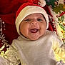 baby, smiling, santa_hat, white_dress, fairy_lights, holiday, christmas, festive, book, red_background, happy, child, cute, indoors, celebration, decoration, person, portrait, joy, holiday_book