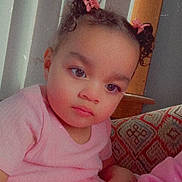 Makiera is registered to the contest to win money with this photo: casual, child, couch, curly_hair, curly_hair_buns, cute, hair_bows, home, indoor, looking_away, patterned_cushion, person, pink_dress, portrait, relaxed, seated, soft_lighting, toddler, young_child, young_girl