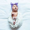 Euphoria is registered to the contest to win money with this photo: newborn, baby, sleeping, wrapped, blanket, headband, purple, bow, infant, peaceful, white, soft, cute, portrait, lying_down, indoors, child, adorable, resting, young