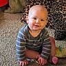 baby, child, infant, smiling, sitting, portrait, carpet, living_room, cushions, leopard_print, striped_clothing, long_sleeves, toy, bare_feet, hands, face, eyes, indoors, happy, adorable