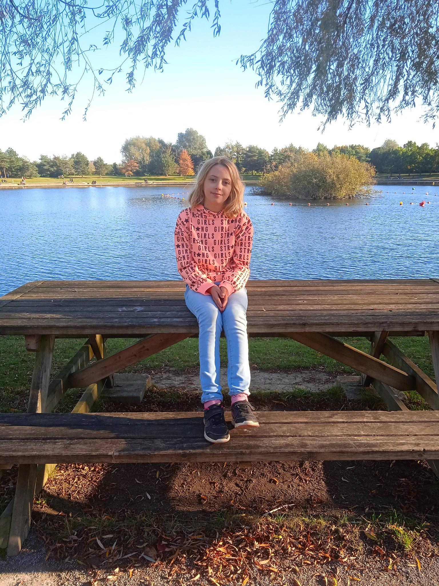 Romane a rejoint le concours — aidez-le/la à gagner de superbes lots ! bank, botany, branch, grass, happy, joy, lake, landscape, leisure, natural_environment, natural_landscape, nature, outdoor_bench, people_in_nature, person, plant, sky, standing, sunlight, tree