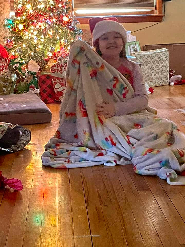 Gemma is registered to the contest to win money with this photo: christmas, christmas_decoration, christmas_eve, christmas_tree, comfort, event, fashion_design, flooring, hardwood, headwear, holiday, joy, laminate_flooring, lap, ornament, peach, person, room, sitting, smile