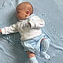 Reggie is registered to the contest to win money with this photo: baby, blue, child, clothing, cozy, cute, face, hand, indoors, infant, knitted_blanket, lying_down, newborn, portrait, sleepwear, small, socks, soft_texture, warm, white