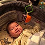 Damien is registered to the contest to win money with this photo: baby, infant, playpen, blanket, toy, smile, face, clothing, sleepwear, indoor, child, cute, soft, pattern, hand, motion_blur, comfort, home, rest, warm