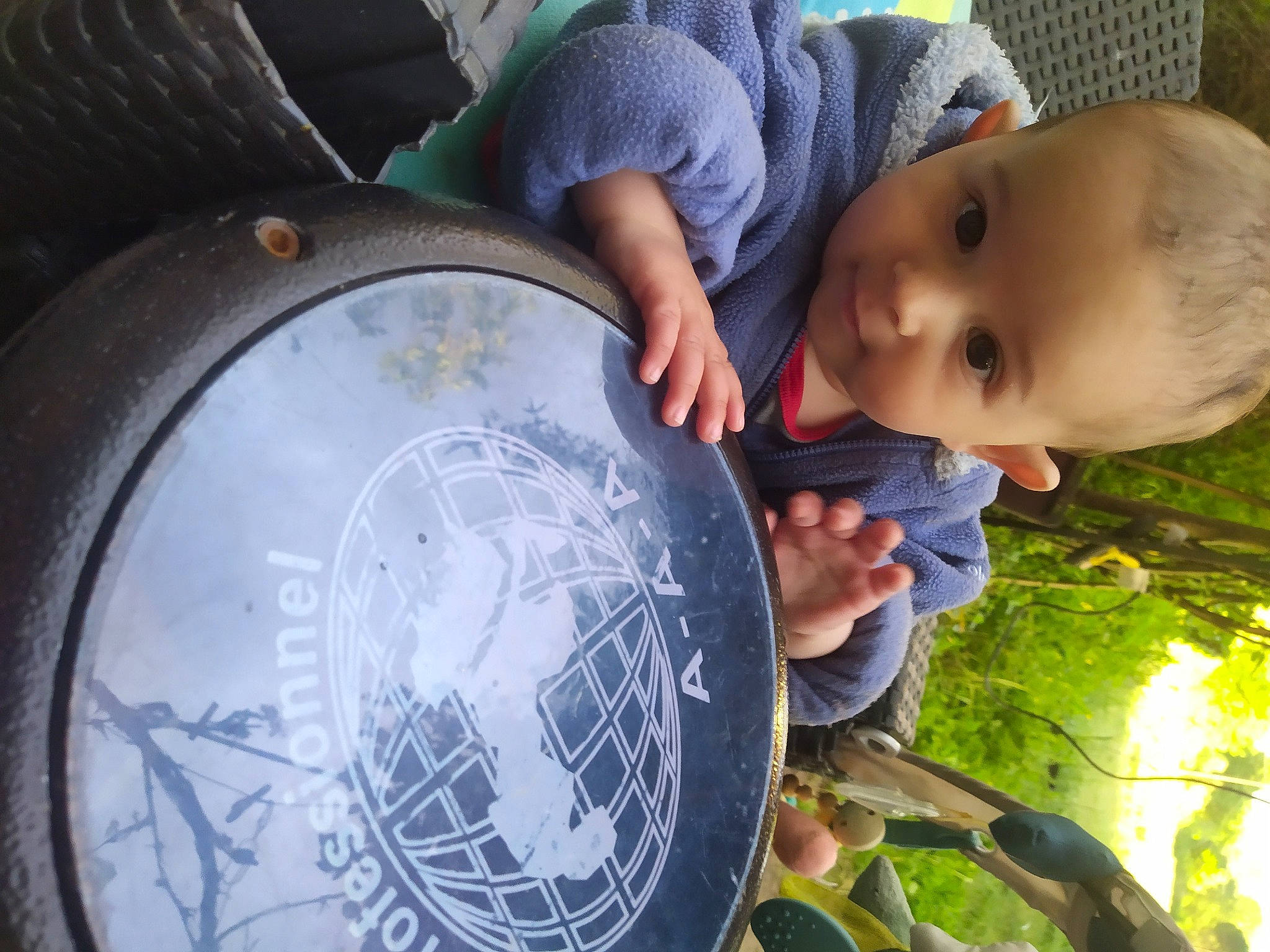 Elio a rejoint le concours — aidez-le/la à gagner de superbes lots ! auto_part, automotive_tire, automotive_wheel_system, baby, baby_toddler_clothing, ball, bass_drum, child, circle, drum, drumhead, electric_blue, fun, grass, green, person, plant, sitting, t_shirt, toddler