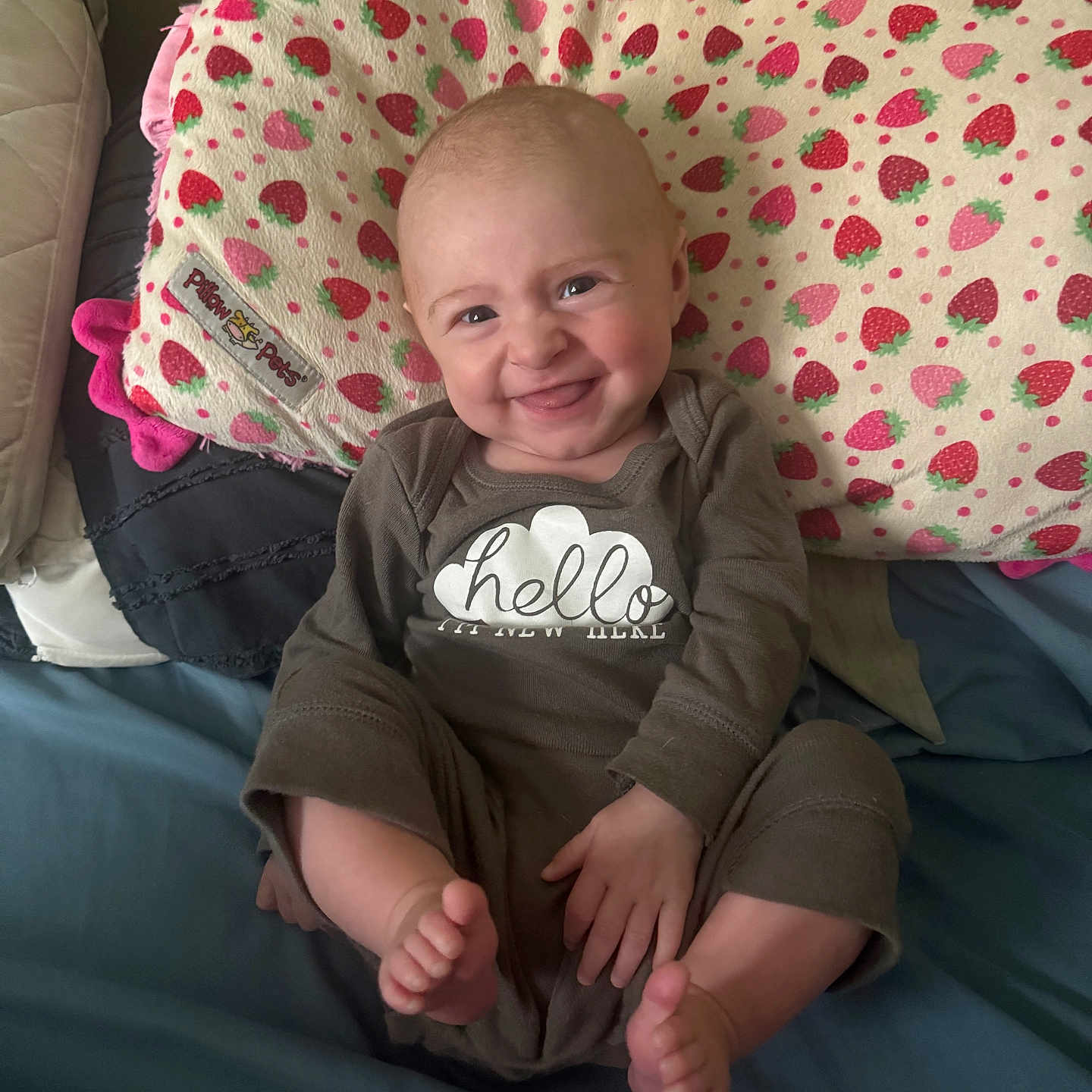 Faith joined the competition — help win amazing prizes! baby, bed, child, clothing, cushion, cute, face, feet, hand, happy, indoors, infant, onesie, person, pillow, playful, relaxed, smiling, soft, strawberry_pattern