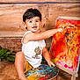 Ezekyel a rejoint le concours — aidez-le/la à gagner de superbes lots ! child, toddler, painting, art, palette, canvas, smiling, happy, barefoot, wooden_floor, white_tank_top, yellow_shorts, indoors, creative, colorful, expression, sitting, person, brush, playful