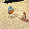 Sonny is registered to the contest to win money with this photo: newborn, baby, sleeping, blue_hat, white_onesie, blanket, fluffy, bed, laundry_bag, clothes, carpet, indoor, rest, infant, cute, cozy, soft, home, person, relaxation