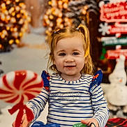 Albanne a rejoint le concours — aidez-le/la à gagner de superbes lots ! background, blue, candy, child, christmas, decorations, festive, happy, holiday, indoor, lights, pigtails, red, smiling, snowman, striped_shirt, toddler, toy, white, winter