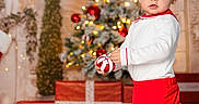 Tyler is registered to the contest to win money with this photo: celebration, child, christmas_tree, curious, cute, decorations, festive, floor, holiday, holiday_lights, indoor, ornament, person, presents, red_shoes, red_shorts, smiling, toddler, white_shirt, winter