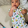Justin joined the competition — help win amazing prizes! baby, child, onesie, couch, pillow, blanket, hand, face, fingers, expression, indoor, clothing, patterned_clothing, cute, infant, relaxing, soft_furnishing, colorful, playful, curious