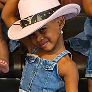 Kelly joined the competition — help win amazing prizes! child, denim_dress, cowboy_hat, smile, earrings, pose, playful, fashion, girl, cute, portrait, indoor, wooden_background, accessory, happy, young, person, denim, jewelry, fun