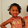 child, girl, smiling, red_dress, gold_embroidery, curly_hair, earrings, posing, happy, portrait, indoor, fashion, elegant, confident, cute, young_girl, celebration, formal_wear, standing, hairstyle