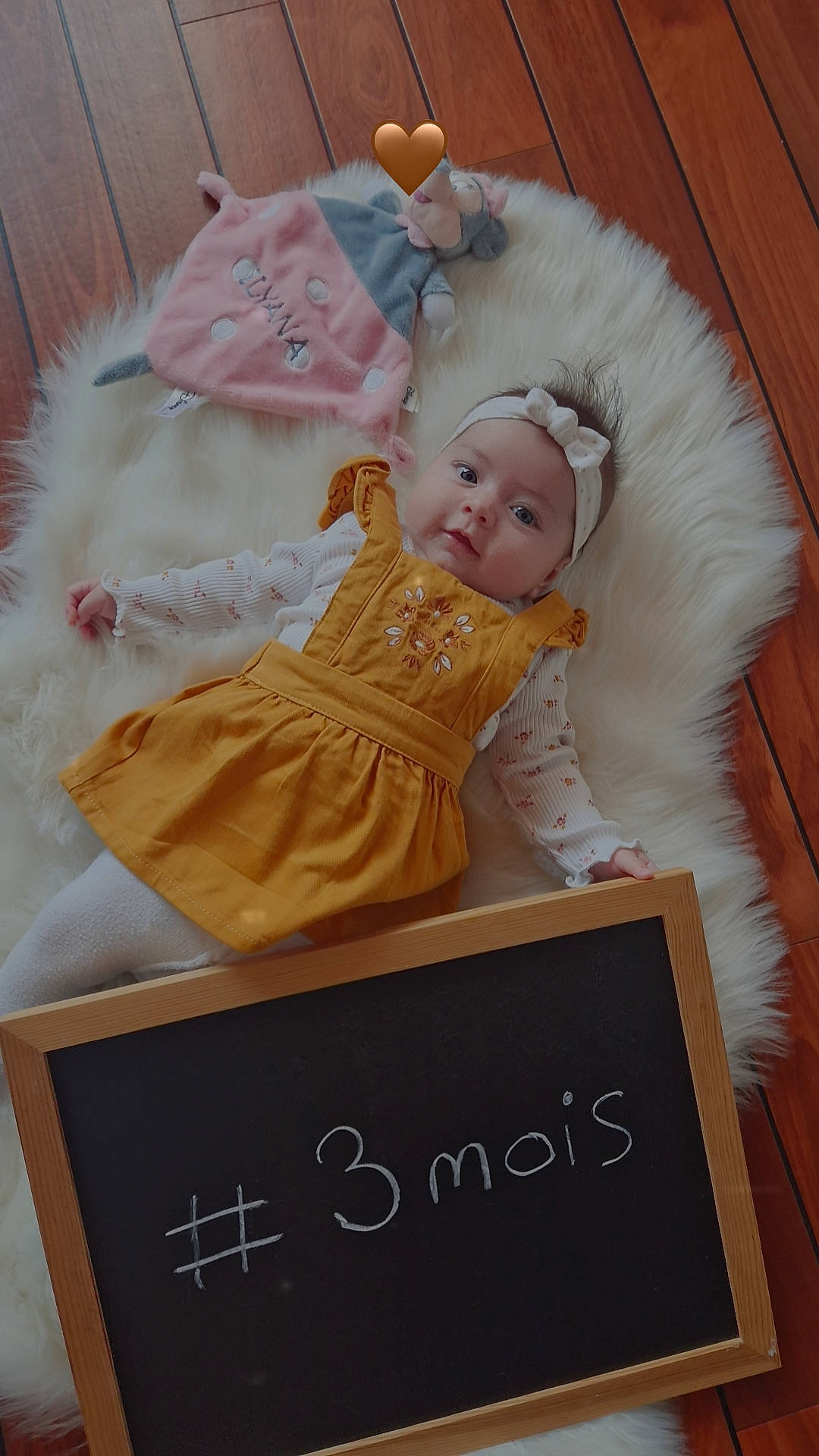 Ilyana participe au concours pour gagner de l'argent avec cette photo : baby, baby_products, baby_toddler_clothing, blackboard, chair, chalk, child, comfort, costume, event, font, fur, handwriting, happy, head, headwear, person, pink, room, sitting