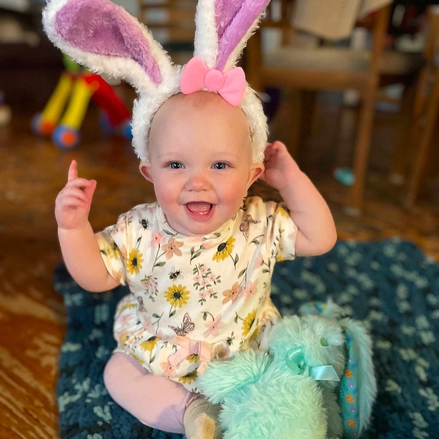 Evalynn joined the competition — help win amazing prizes! baby, bunny_ears, pink_bow, smiling, indoor, blue_blanket, stuffed_toy, wooden_floor, floral_clothing, child, cute, happy, sitting, toy, headwear, face, infant, plush_toy, decor, person