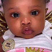 Mailan is registered to the contest to win money with this photo: baby, child, face, portrait, close_up, cute, infant, girl, clothing, white_outfit, glitter, gold, crown, badge, sparkle, pink, eyes, cheeks, expression, soft_background