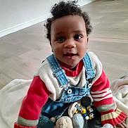 Ayan participe au concours pour gagner de l'argent avec cette photo : baby, baby_bottle, blanket, casual_clothing, child, cozy, curly_hair, cute, denim_overalls, floor, happy, indoor, playtime, portrait, red_sweater, seated, smiling, soft_toy, toddler, toy
