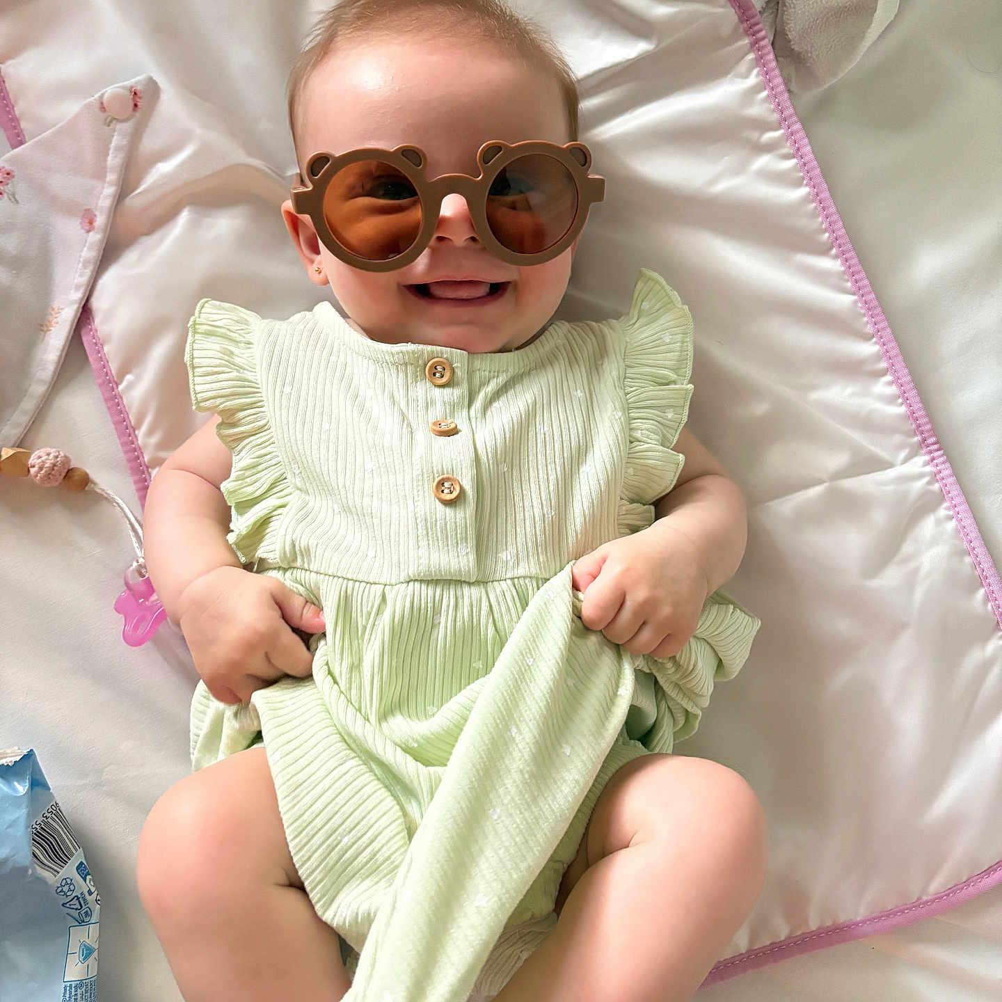 Sophie participe au concours pour gagner de l'argent avec cette photo : accessory, baby, child, comfort, cute, hands, happy, head, indoor, legs, light_green, lying_down, pink_border, playful, ruffled_dress, skin, smiling, sock, soft_mat, sunglasses