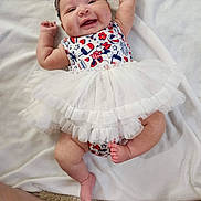 Kalista joined the competition — help win amazing prizes! baby, smiling, infant, tutu, headband, white_blanket, barefoot, lying_down, happy, cute, chubby_legs, clothing, patterned_outfit, person, young_child, indoors, soft_texture, skin, face, playful