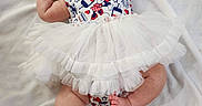 Kalista joined the competition — help win amazing prizes! baby, barefoot, chubby_legs, clothing, cute, face, happy, headband, indoors, infant, lying_down, patterned_outfit, person, playful, skin, smiling, soft_texture, tutu, white_blanket, young_child