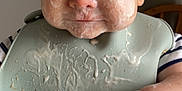 Cohen is registered to the contest to win money with this photo: baby, messy, food, bib, high_chair, face, hand, feeding, infant, child, meal, expression, cute, smear, skin, table, clothing, indoor, portrait, dining