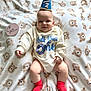 Cohen joined the competition — help win amazing prizes! baby, infant, smile, hat, party_hat, onesie, red_socks, blanket, bear_pattern, cute, child, lying_down, celebration, indoors, happy, face, skin, small_person, wearing_clothes, cozy
