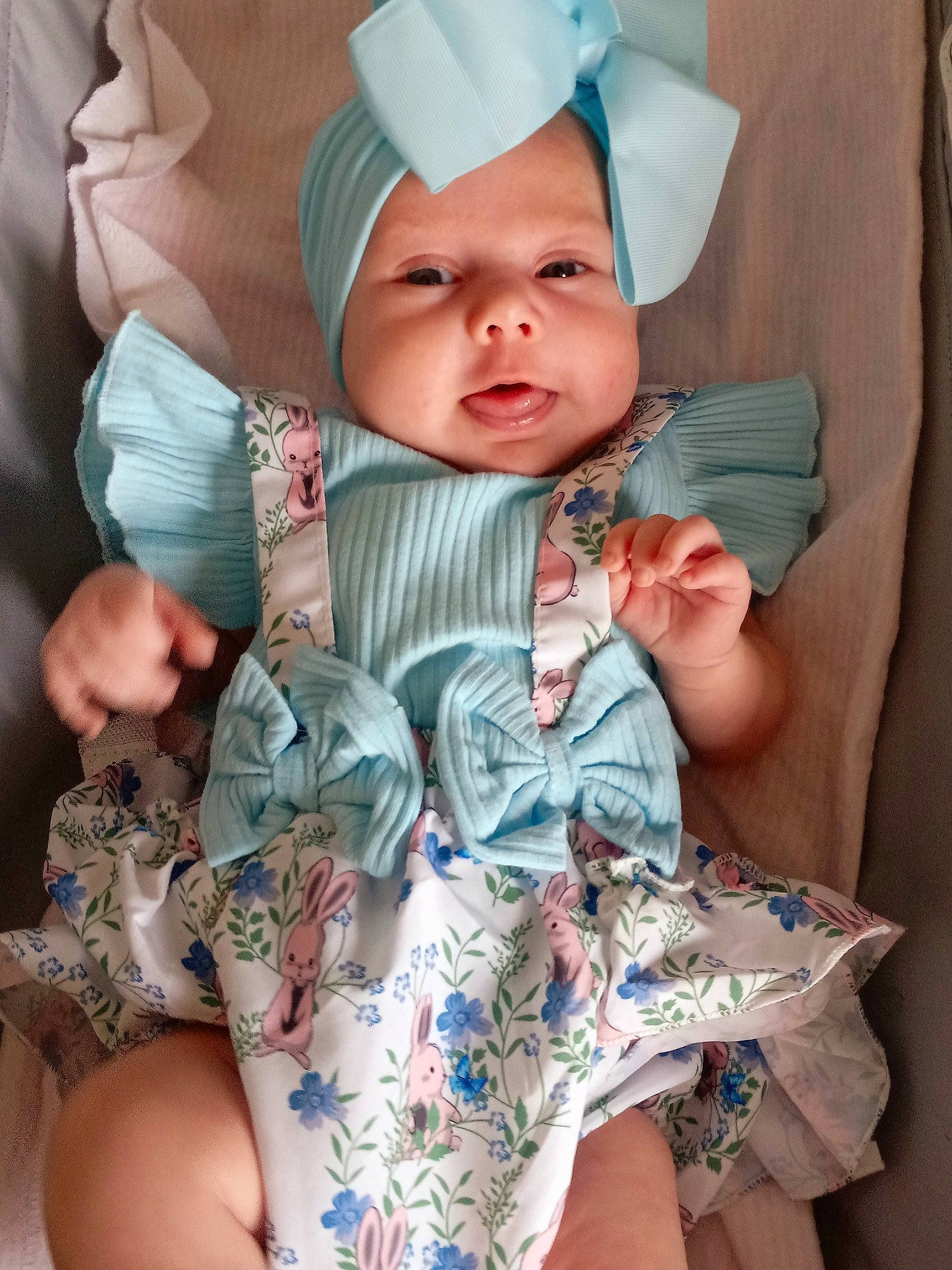 Amelia is registered to the contest to win money with this photo: arm, baby, baby_toddler_clothing, cap, chair, child, collar, comfort, dress, eye, face, finger, head, headwear, human_body, linens, person, pink, skin, sleeve