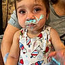 toddler, child, cream, face_paint, blue_tutu, colorful_clothing, indoor, person, sitting, cute, expression, closeup, smile, funny_face, baby, arm, clothing, cartoon_print, food_mess, parent