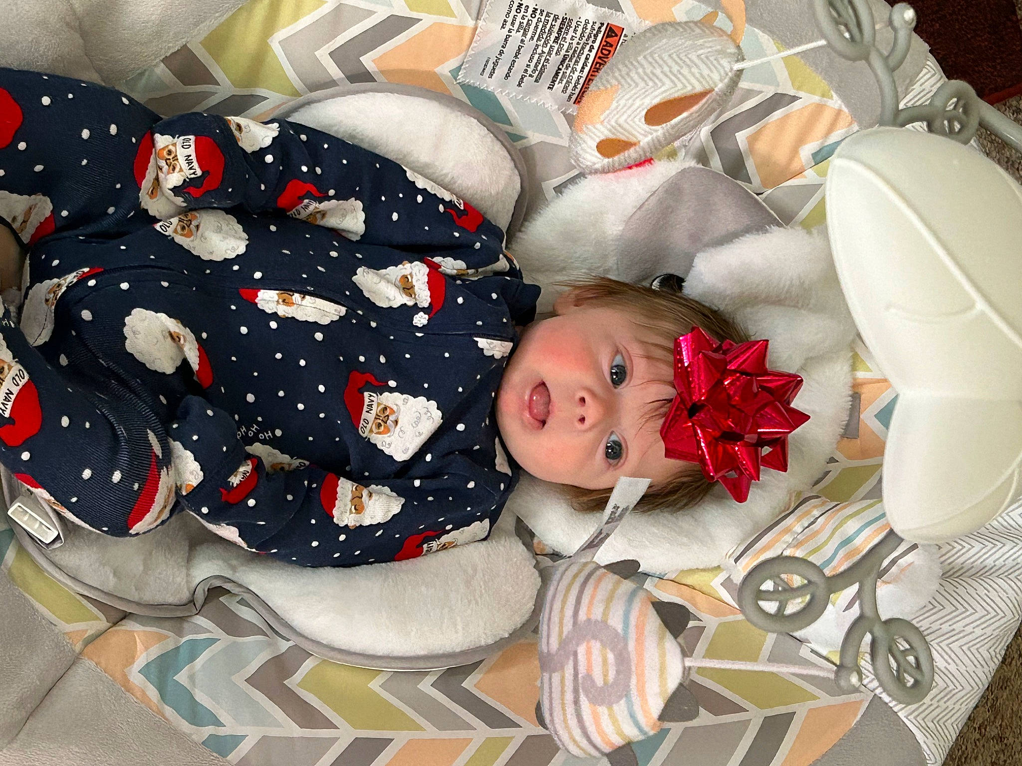 Winston is registered to the contest to win money with this photo: baby, baby_products, baby_toddler_clothing, carmine, child, comfort, flooring, headwear, lap, linens, pattern, person, room, sleeve, smile, surprise, toddler