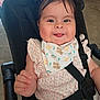 baby, child, smile, tongue_out, stroller, bib, clothing, face, hair, hand, safety_strap, seat, indoor, happy, cute, infant, person, portrait, young_child, playful