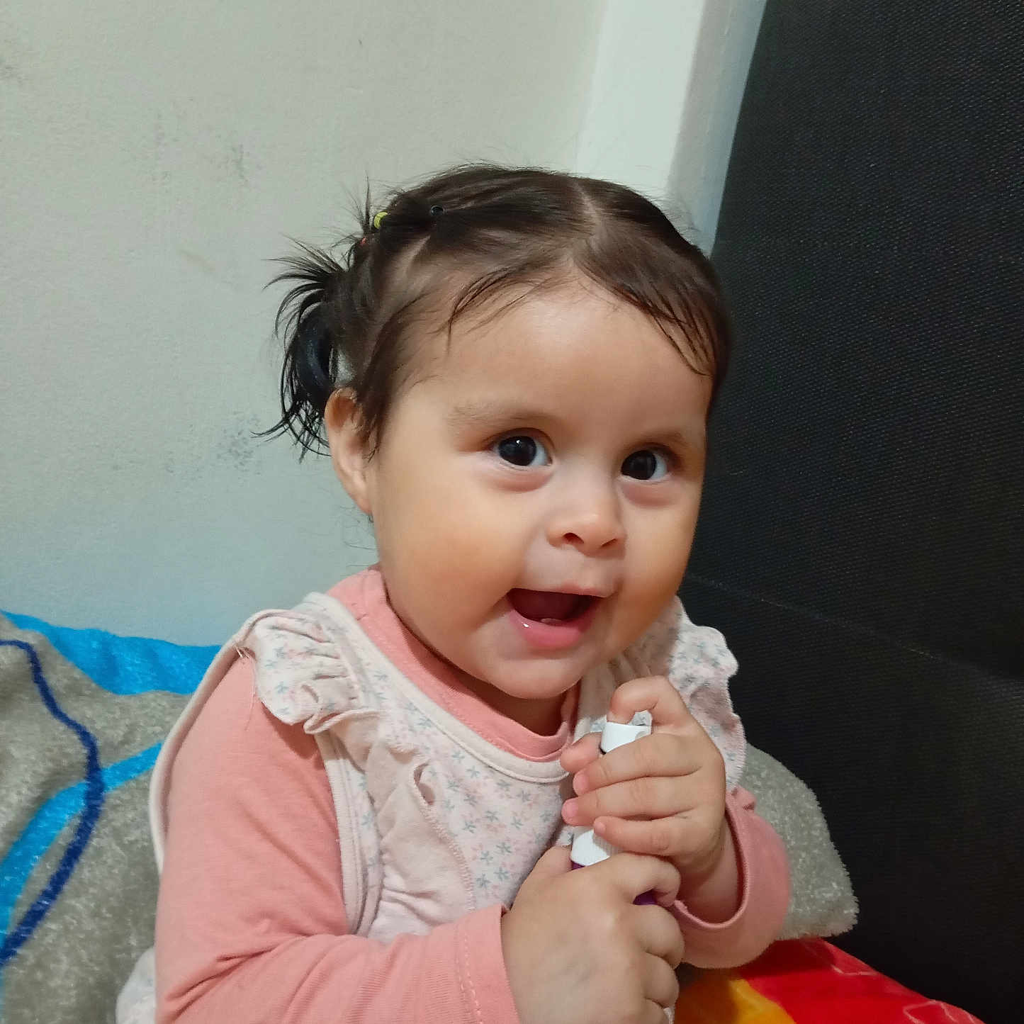 Laya Aurora is registered to the contest to win money with this photo: baby, blanket, child, clothing, cushion, cute, face, happy, holding, indoors, person, pigtails, pink, portrait, purple, sitting, smiling, toddler, wall, young_child