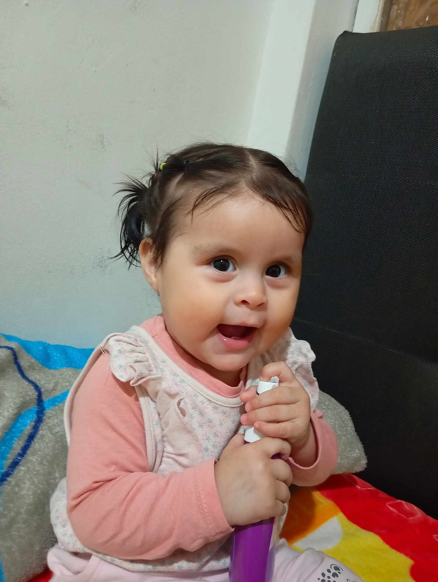 Laya Aurora is registered to the contest to win money with this photo: toddler, child, baby, cute, smiling, pigtails, indoors, blanket, cushion, wall, face, person, clothing, sitting, holding, pink, purple, happy, young_child, portrait