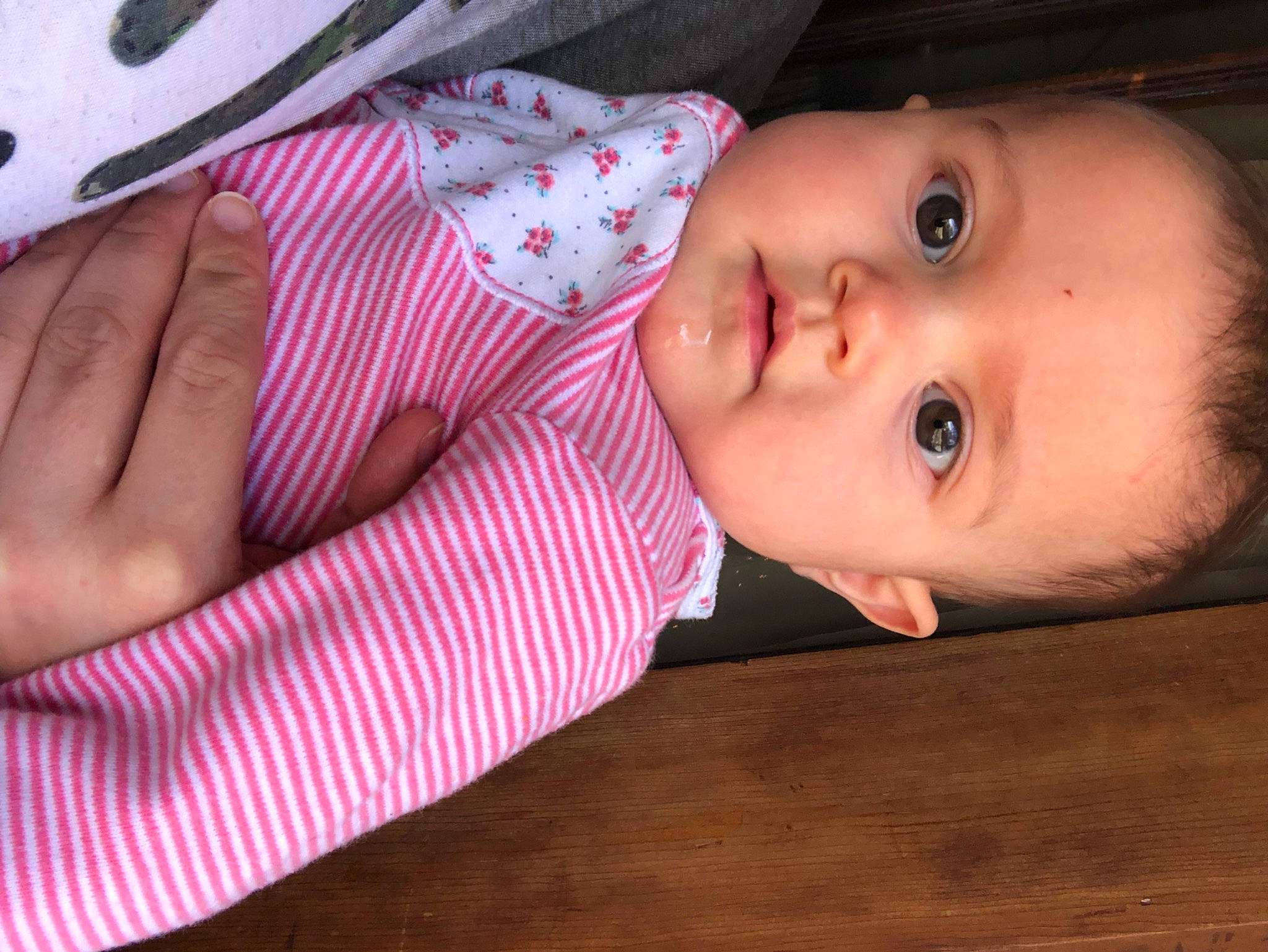 Luella is registered to the contest to win money with this photo: baby, baby_toddler_clothing, cheek, child, comfort, eye, eyelash, flooring, hardwood, iris, linens, lip, nose, pattern, person, pink, skin, sleeve, smile, toddler