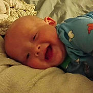 Ellis joined the competition — help win amazing prizes! baby, smile, blue_shirt, blanket, infant, lying_down, happy, child, bed, soft_texture, cute, indoors, skin, head, face, person, apparel, toddler, comfort, young_child