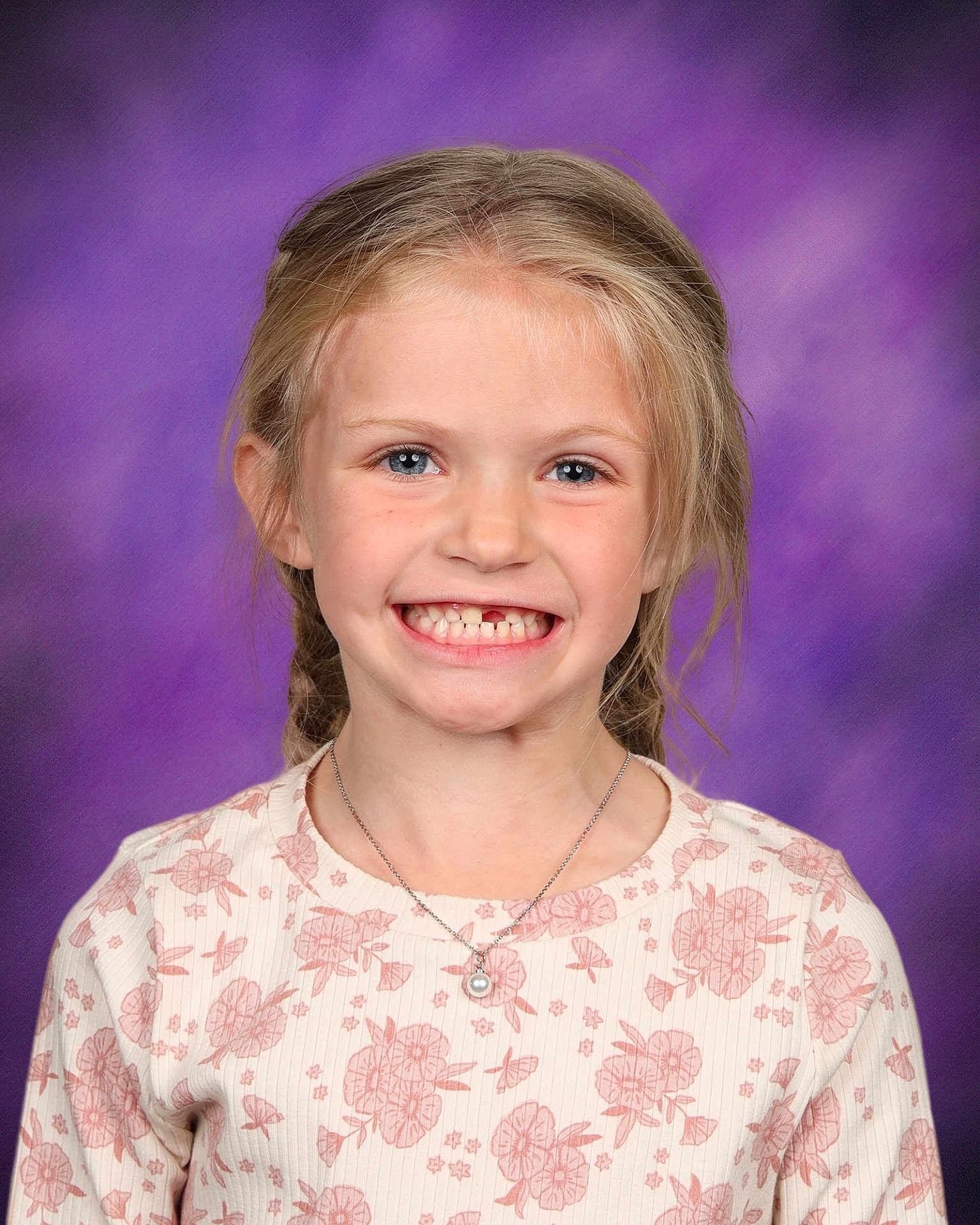 Quinn is registered to the contest to win money with this photo: child, girl, smiling, portrait, braids, missing_tooth, necklace, floral_pattern, long_sleeves, blue_eyes, blonde_hair, studio_background, purple_background, happy, cute, school_photo, casual_clothing, young, female, face