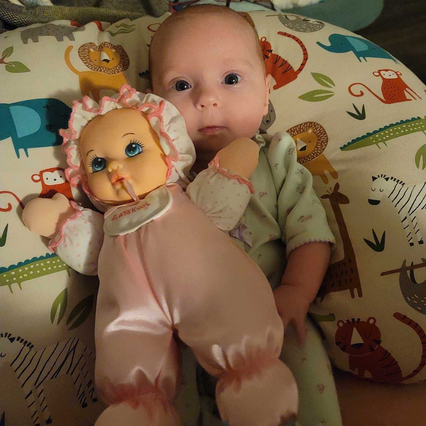 Daisy is registered to the contest to win money with this photo: baby, doll, pillow, animal_print, infant, child, toy, pink_clothing, sleepwear, face, eyes, lying_down, cute, soft_lighting, indoor, fabric, pattern, hand, head, comfort