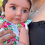 Brooklyn is registered to the contest to win money with this photo: adult, baby, child, closeup, clothing, cross, cute, expression, face, floral, hair, hand, holding, infant, natural_light, necklace, outdoor, person, portrait, skin
