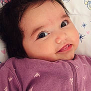 Brooklyn is registered to the contest to win money with this photo: baby, blanket, cheeks, child, closeup, clothing, cute, eyes, face, hair, happy, indoors, infant, lying_down, pattern, portrait, purple, smiling, soft_lighting, young