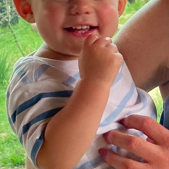 Stetson joined the competition — help win amazing prizes! adult_hand, baby, blonde_hair, casual_clothing, child, cute, daylight, expression, face, greenery, happy, holding, nature, outdoor, person, portrait, skin, smiling, striped_shirt, toddler