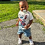 toddler, child, pacifier, standing, outdoor, grass, concrete, sunlight, shorts, tshirt, white_shoes, casual_clothing, cute, portrait, daylight, young_child, happy, small_pony_tail, sidewalk, summer