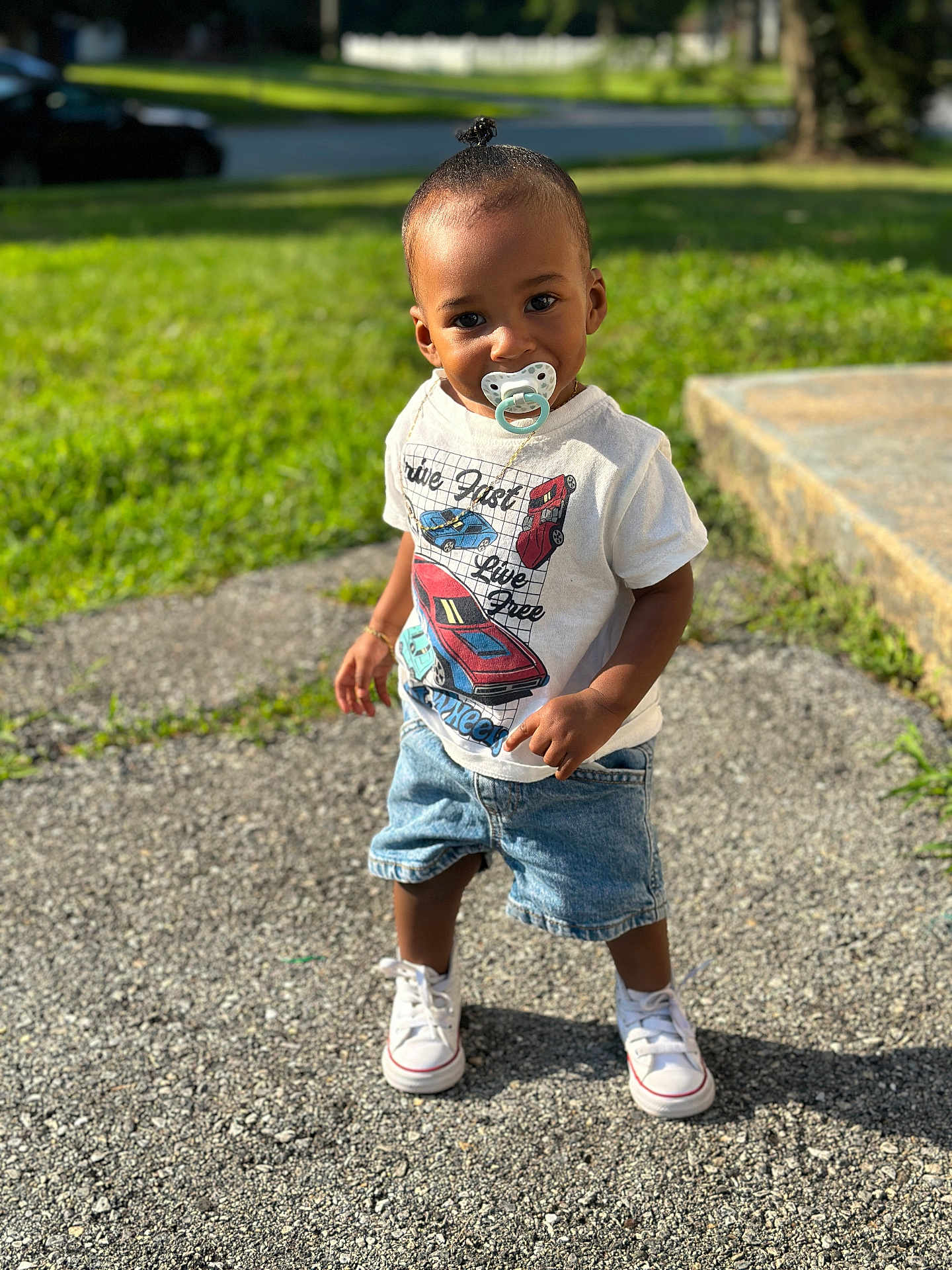 Kross is registered to the contest to win money with this photo: toddler, child, pacifier, standing, outdoor, grass, concrete, sunlight, shorts, tshirt, white_shoes, casual_clothing, cute, portrait, daylight, young_child, happy, small_pony_tail, sidewalk, summer