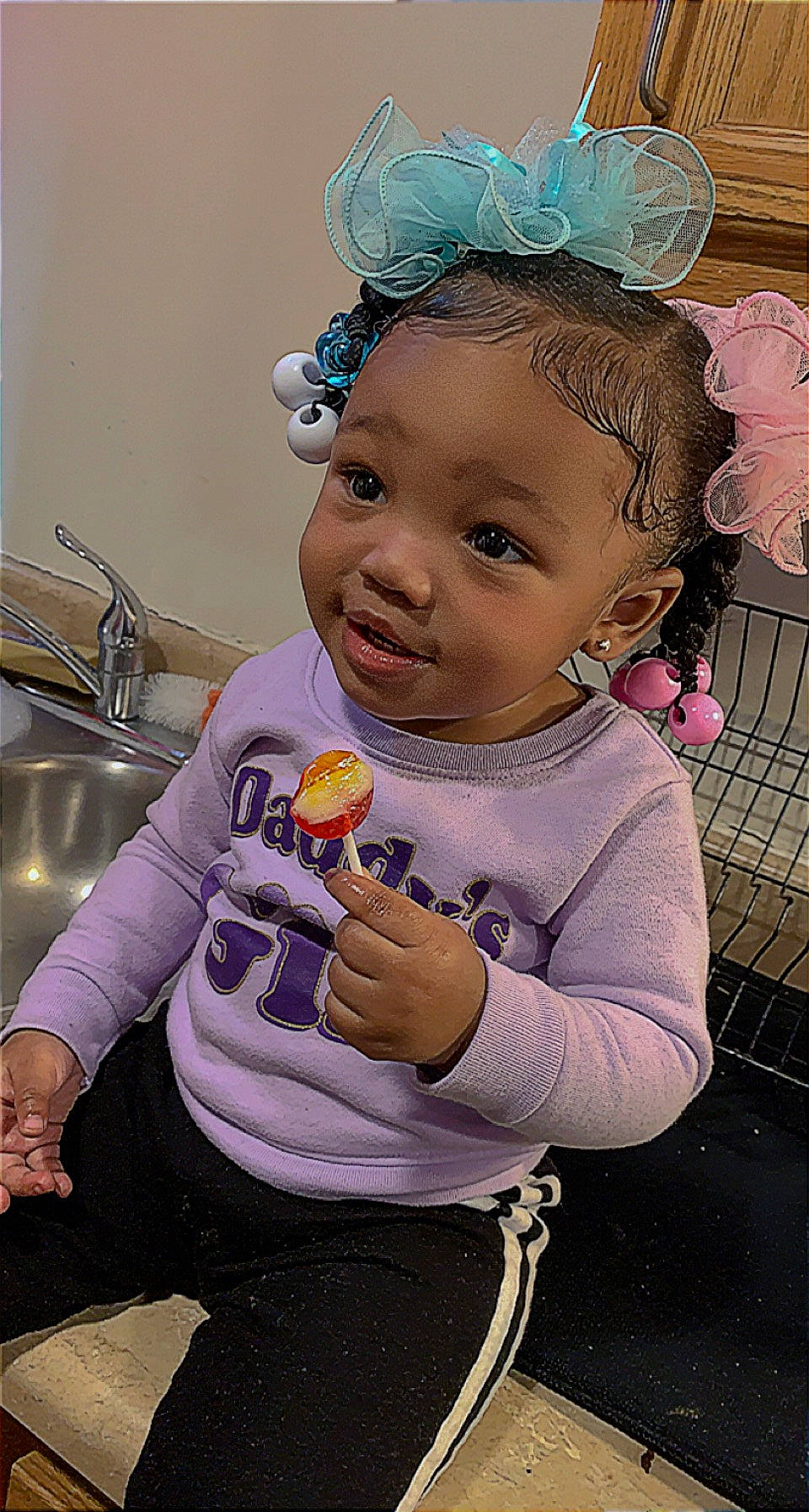 Dalayiah is registered to the contest to win money with this photo: arm, baby, baby_toddler_clothing, cheek, child, clothing, eyelash, fashion_accessory, fun, happy, headband, headgear, headpiece, jewellery, person, pink, purple, sitting, skin, sleeve