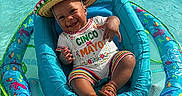 Jamarcus joined the competition — help win amazing prizes! baby, celebration, child, clothing, colorful, cute, float, fun, happy, hat, holiday, inflatable, outdoor, pool, sandals, sitting, smiling, sombrero, summer, water