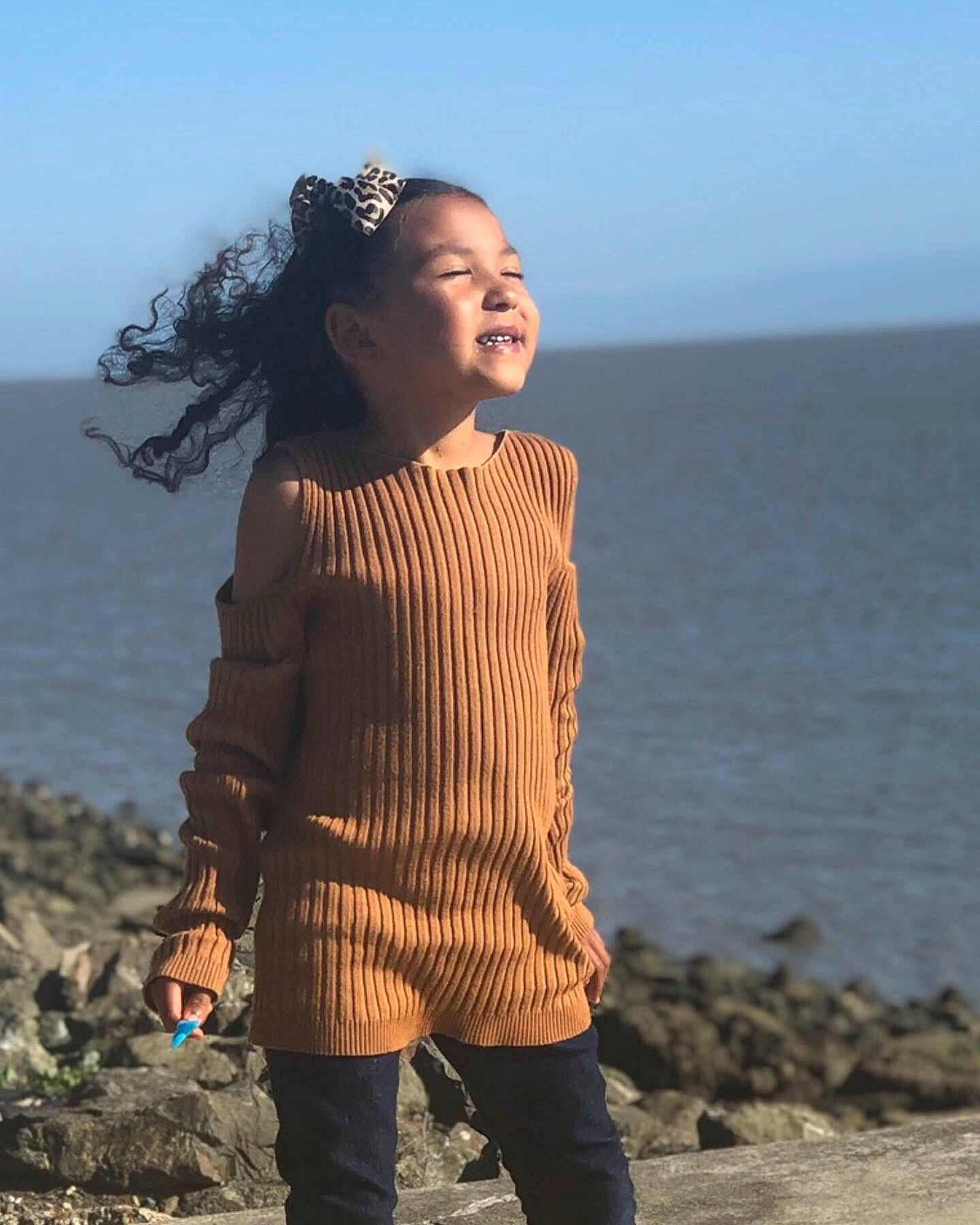 Jordynn is registered to the contest to win money with this photo: beach, fawn, happy, neck, ocean, outerwear, person, photography, sea, sky, sleeve, smile, standing, vacation