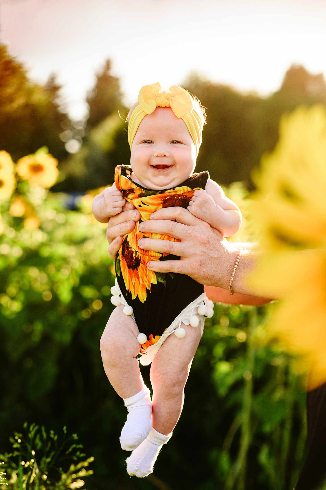 Kamryn is registered to the contest to win money with this photo: baby, infant, child, sunflower, headband, outdoor, garden, flower, smiling, person, hands, summer, nature, greenery, sunlight, socks, cute, happy, holding, portrait